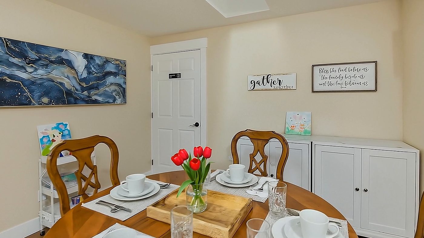 The dining table set for a shared meal, with red tulips and a sign on the wall that reads gather.