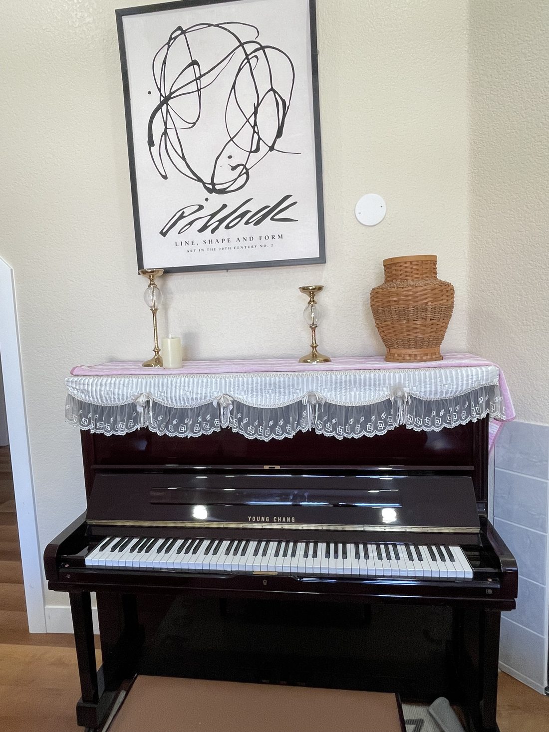The piano in a quiet corner of the living room, with candlesticks and a framed print above it.